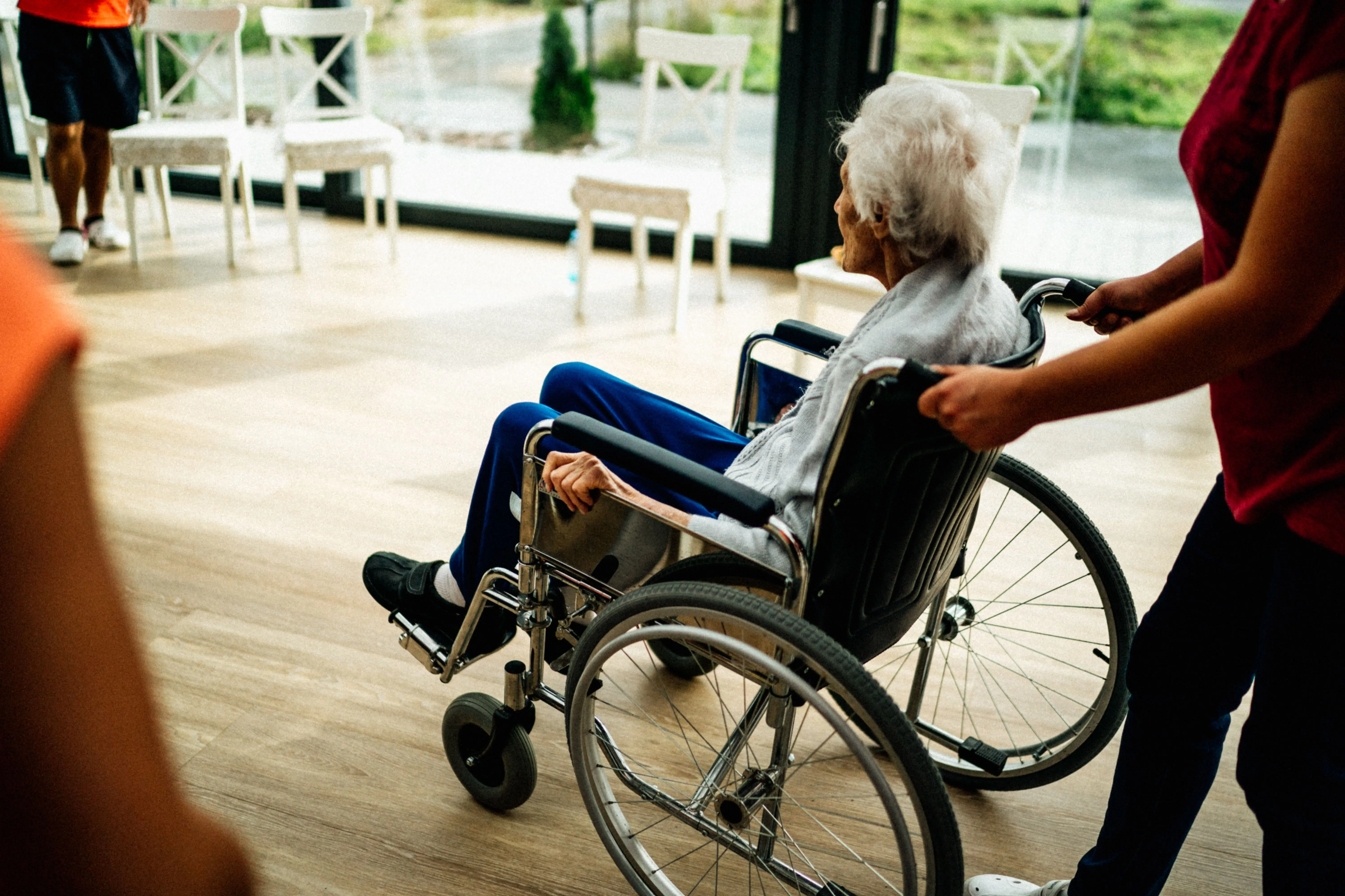 A caregiver walking with an elderly woman using a walker